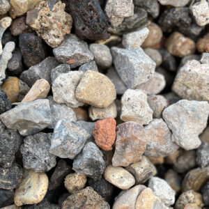 Close-up of 10/20 recycled aggregate from Runfold, Farnham: small, rough stones in grey, black, brown, and reddish tones.