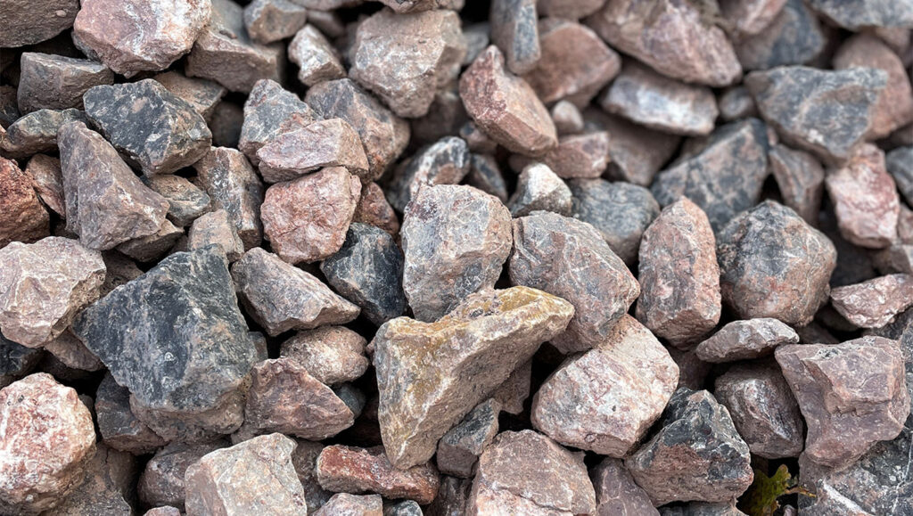 Close-up of rough, mixed grey, pink, and brown Type 1 Limestone Clause 803 aggregate in Runfold, Farnham, Surrey.