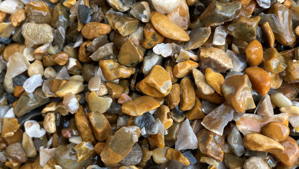 Wet, multicoloured 4–10mm gravel pebbles from Runfold, Surrey in brown, tan, grey, and white with a glossy look.