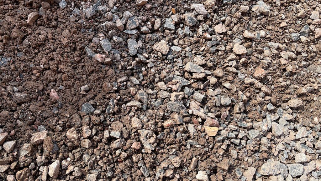 Close-up of Limestone Scalpings on soil in Runfold, Surrey, showing small rocks, pebbles, and coarse earth with rough textures.