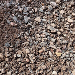 Close-up of Limestone Scalpings on soil in Runfold, Surrey, showing small rocks, pebbles, and coarse earth with rough textures.